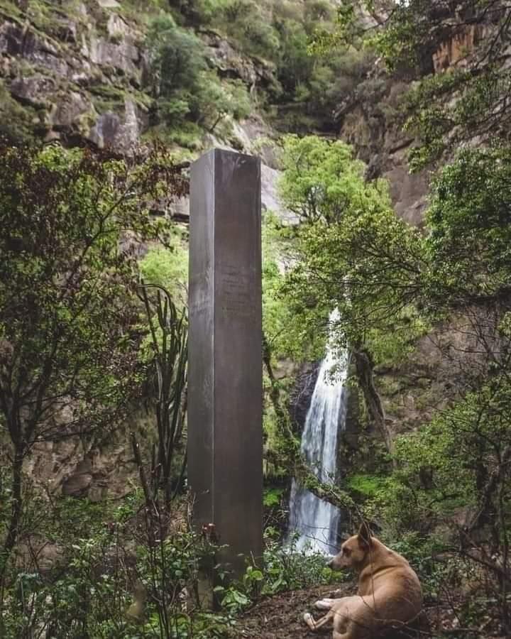 Monolito misterioso con cascada natural y perro feliz.